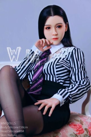 Kailey 158cm in a striped blouse and black skirt, sitting with one leg crossed, wearing a tie.