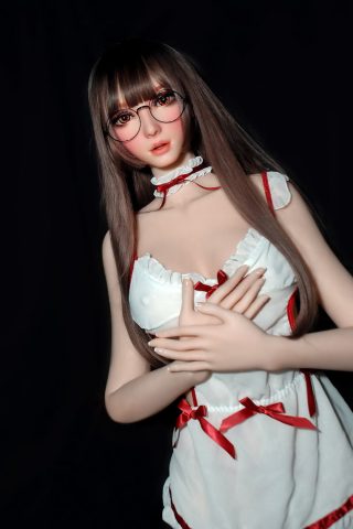 Masako – 165cm Elsa Babe silicone sex doll wearing a white dress with red ribbons and glasses, posing with hands clasped.