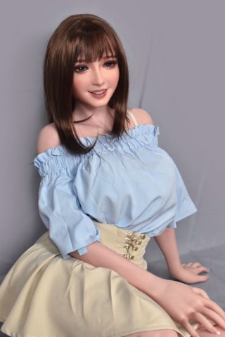 Nagasawa – 150cm Elsa Babe Silicone Sex Doll wearing a light blue off-shoulder top and a cream skirt, seated with a smile.