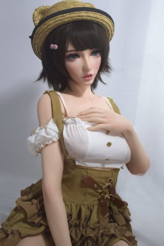 Sawako – 150cm Elsa Babe Silicone Sex Doll wearing a white top and brown dress with ruffles, seated with a hat.