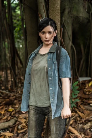 Ellie The Last of Us doll stands 5 feet tall, wearing a faded blue shirt and green top, holding a bow in a forest setting.