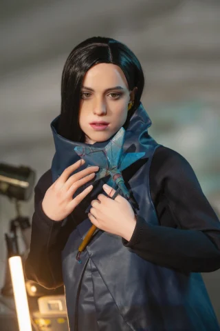 Lockne doll holding a blue star-shaped object, wearing a dark coat with a high collar, set against a blurred background.