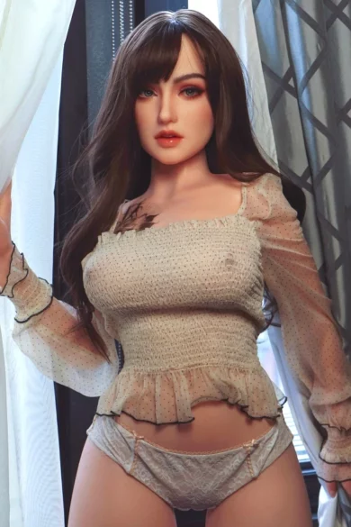 A love doll in a sheer outfit poses by a window with patterned curtains, showcasing the XNX Georgina 162cm X10 model.