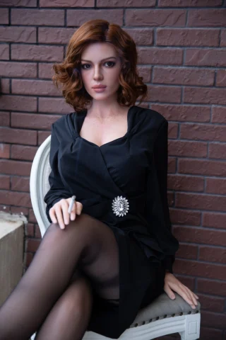 Wayner Starpery 172 F Cup sitting with legs crossed, wearing a black dress and holding a cigarette, against a brick wall.