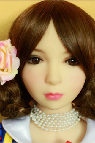 Snow White doll with brown hair and a pink flower, wearing a colorful dress and pearl necklace.