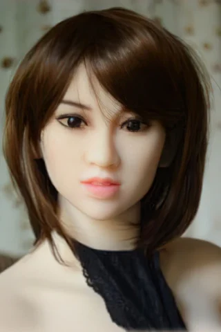 135cm doll with short brown hair and a black lace top, featuring a neutral expression against a blurred floral background.