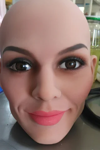 Bald mannequin head with realistic facial features, including brown eyes, defined eyebrows, and pink lips.