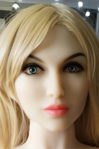 Doll head with blonde hair and blue eyes, featuring a neutral expression and subtle pink lips.