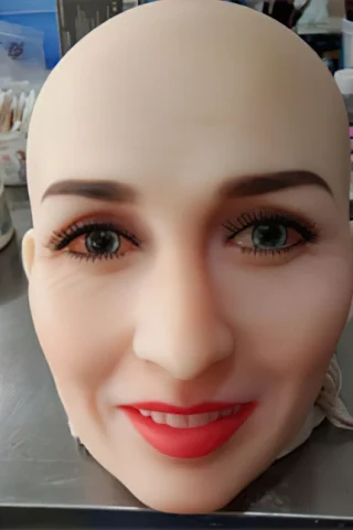 Bald silicone head with realistic facial features, including bright eyes and red lips, set on a table.