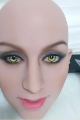 213 doll head with green eyes, featuring detailed makeup and a smooth bald scalp.