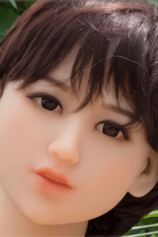 Doll head with short brown hair and dark eyes, set against a green background.
