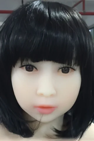 301 doll with short black hair, featuring a smooth face and neutral expression, displayed in a factory setting.