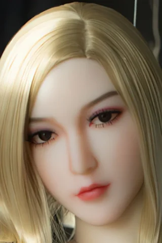 390 doll with long blonde hair and soft facial features, wearing a neutral expression against a blurred background.