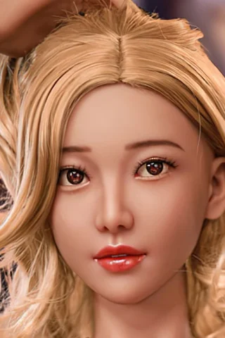 Doll with long blonde hair and brown eyes, wearing a natural expression and posing with one hand in her hair.
