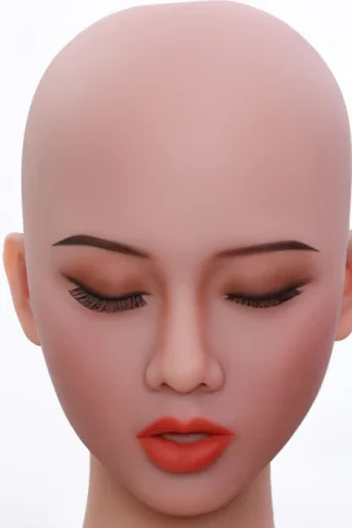 Doll head with closed eyes, smooth skin, subtle makeup, and red lips against a plain background.