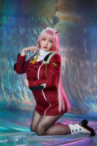 Oria 165cm poses on one knee, wearing a red military-style outfit with a white collar and pink hair.