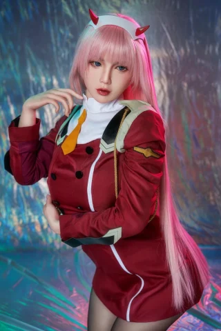 Oria 165cm F Cup wearing a red military-style outfit with a white collar and long pink hair, posing against a reflective background.