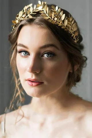 Greek Leaf Crown, featuring a gold design with intricate leaf details, worn by a woman with soft makeup and wavy hair.
