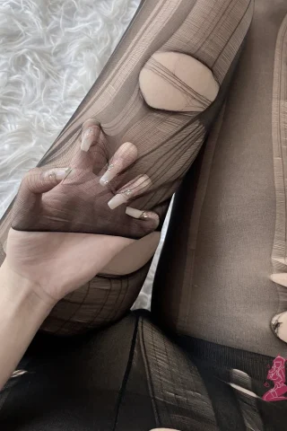 Ripped stockings with large holes, featuring a hand reaching through, set against a soft white background.