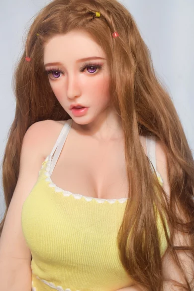 Nagashima Sawako 150cm ElsaBabe sex doll with XL breasts, long brown hair, vibrant violet eyes, in a yellow top with white straps against a plain background