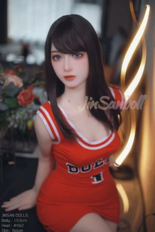 Jinsan 153cm B Cup #462 in a red sports dress, sitting with a soft expression beside a decorative light.