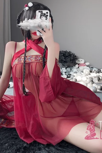 Sex doll in bold red Arabic see-through outfit on furry rug taking mirror selfie with scattered silver and white balls in the room.