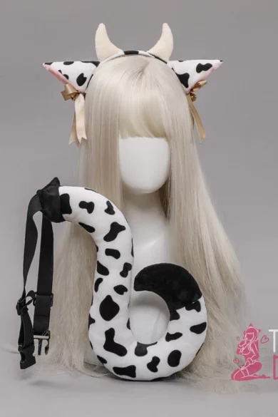 Mannequin with long blonde wig wearing cow-print horns and ears, holding matching curved tail; promotes cow ears, horns & tail product.