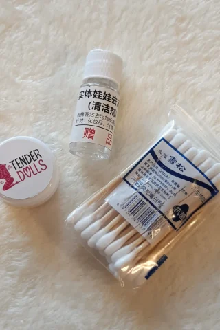 Tender Dolls TPE Stain Remover with a small bottle, a jar, and a pack of cotton swabs on a soft surface.