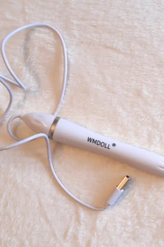 WM Doll USB Heater with a white body and a USB cable, resting on a soft, light-colored surface.