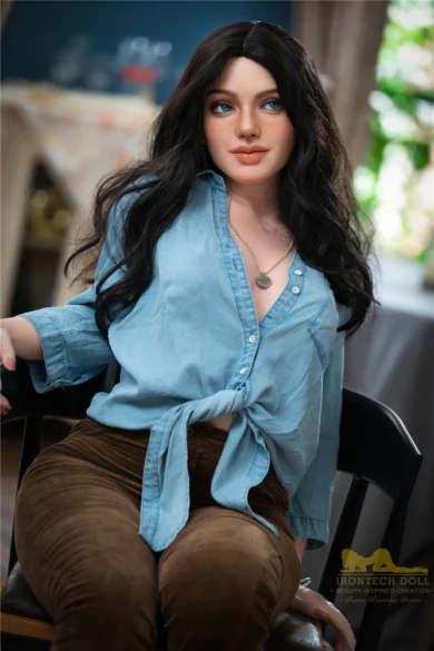 Ivy S27 152cm Irontech sex doll with long dark hair, denim shirt tied at the waist, seated on a black chair indoors