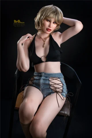 Irontech Doll, 160cm, wearing a black halter top and denim shorts, seated on a chair against a dark background.