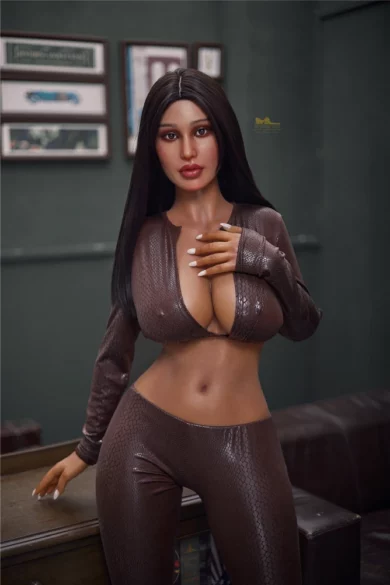 Woman with long dark hair in shiny brown outfit poses indoors near a table with frames on wall embodying elegance of Pearl S19 165cm Irontech sex doll