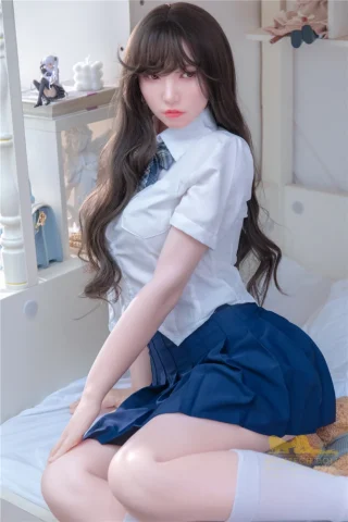 Hazel S18 166cm B Cup Irontech in a school uniform, seated on a bed with long hair and a playful expression.