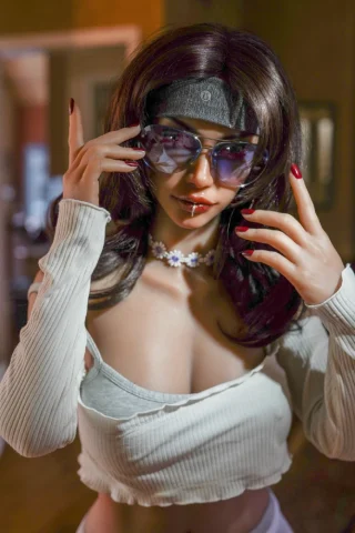 YL 158cm Isla Silicone doll wearing white leggings and a cropped white top, with sunglasses and a necklace, posing indoors.