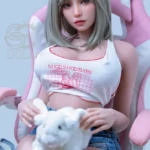 Blonde-haired figure in a pink chair wearing a white crop top, holding a white plush toy, resembles Akina 157cm H Cup SE Doll