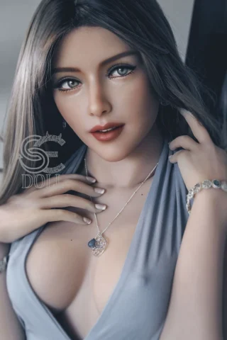 Blanche 163cm E Cup doll with long brown hair, wearing a low-cut gray dress, adorned with jewelry and a subtle smile.