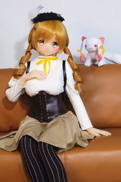 A love doll named Akeno with blonde pigtails and 150cm D Cup #70 Head sits on a couch with a plush toy