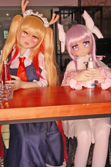 Two figures in colorful costumes sit at a table holding bottles, wearing anime-style wigs and accessories resembling Noriko 155cm F & Fat Cup #51 and #52 love dolls.