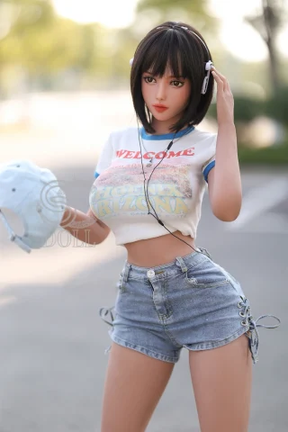 SED233 161cm Stella doll wearing a white graphic t-shirt and denim shorts, with headphones and a cap in hand.