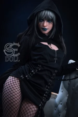 Heloise 166cm B Cup SE Doll dressed in gothic attire with hood, dark makeup, and fishnet stockings sitting on chair against shadowy background