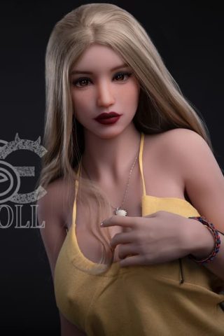 Amelia 161cm F Cup SE Doll poses in a yellow tank top with long blonde hair and subtle makeup.