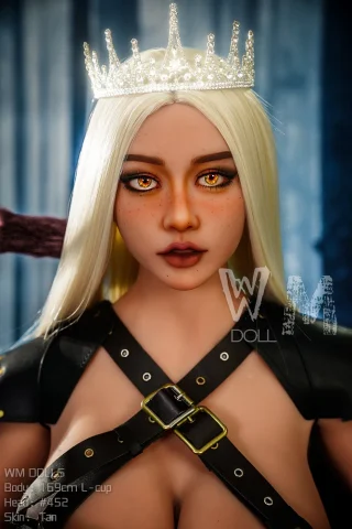 WM Doll 169cm L Cup #452 features tan skin, long blonde hair, and striking orange eyes, adorned with a crown and leather straps.