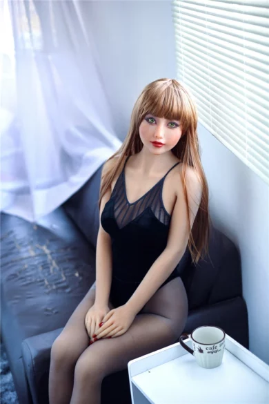 Saya 163cm C Cup Irontech TPE doll in black outfit seated on couch near table with coffee cup by blinds-covered windows