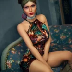 Plus scarlet 164cm E Cup Irontech TPE love doll with striking makeup and headwrap, seated on floral-patterned sofa