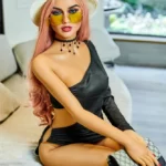 Selina 165cm A Cup Irontech TPE doll on sofa wearing black dress, sunglasses, chic hat, holding purse.