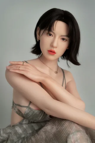 GE123 170cm C Cup Zelex Doll poses with one arm draped over her shoulder, wearing a sheer, light green dress.