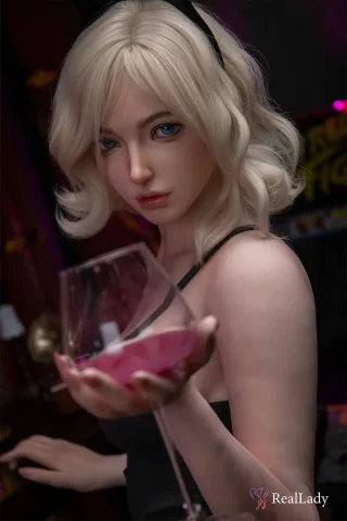 Min S41 170cm holds a glass of pink drink, wearing a black dress with wavy blonde hair and blue eyes.