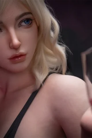 Min S41 170cm RealLady holding a glass with pink liquid, featuring blonde hair and blue eyes, in a dimly lit setting.