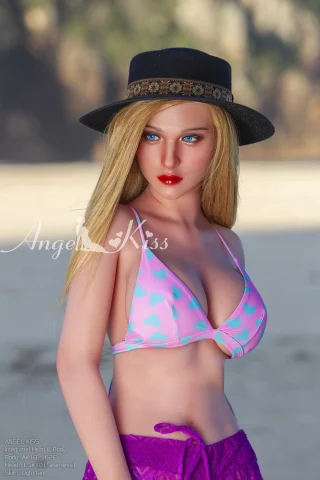 Angel Kiss 5ft5 doll wearing a pink heart-patterned bikini with a purple sarong and a wide-brimmed hat at the beach.