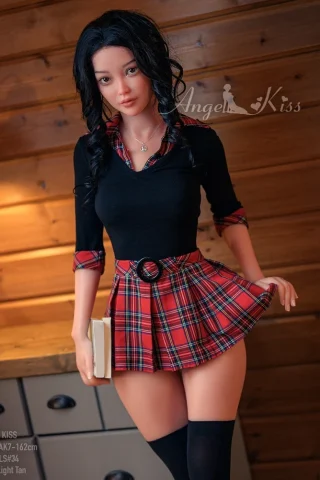AK162 5ft5 Silicone Angel Kiss doll wearing a black top and a plaid skirt, holding a book in a wooden setting.